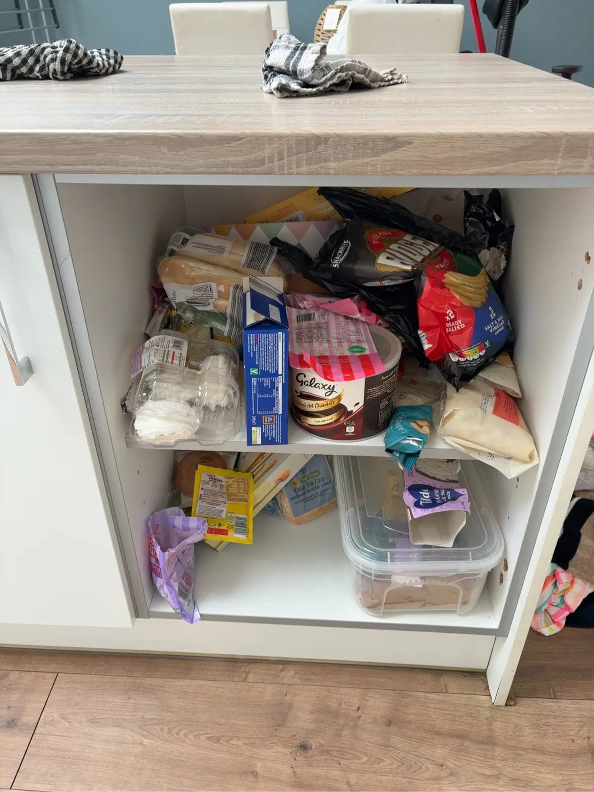 The customer’s original food cupboard with loose bread, snacks, packets and groceries stacked together