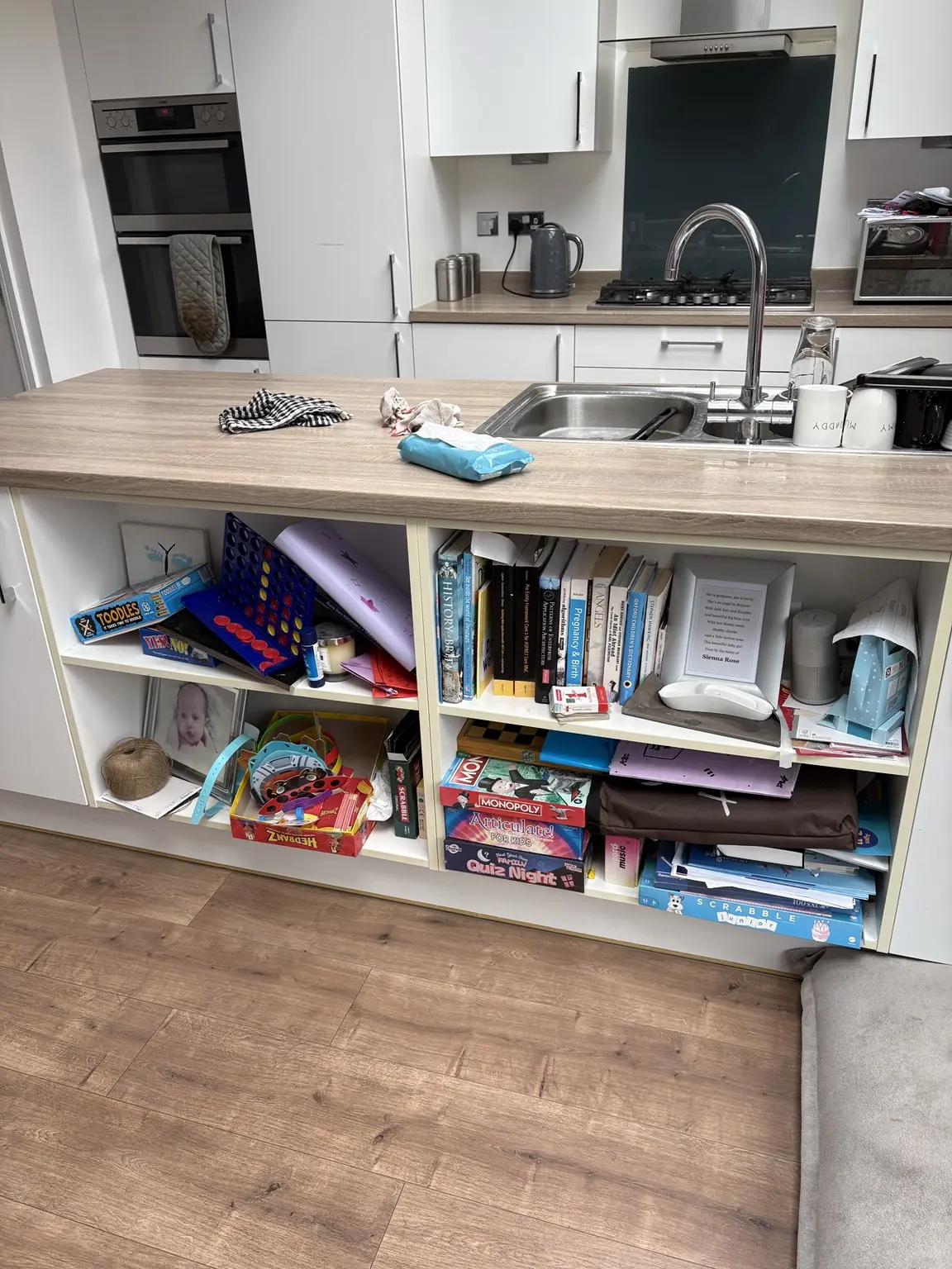 The customer’s original kitchen shelves containing mixed games, books, papers and loose items